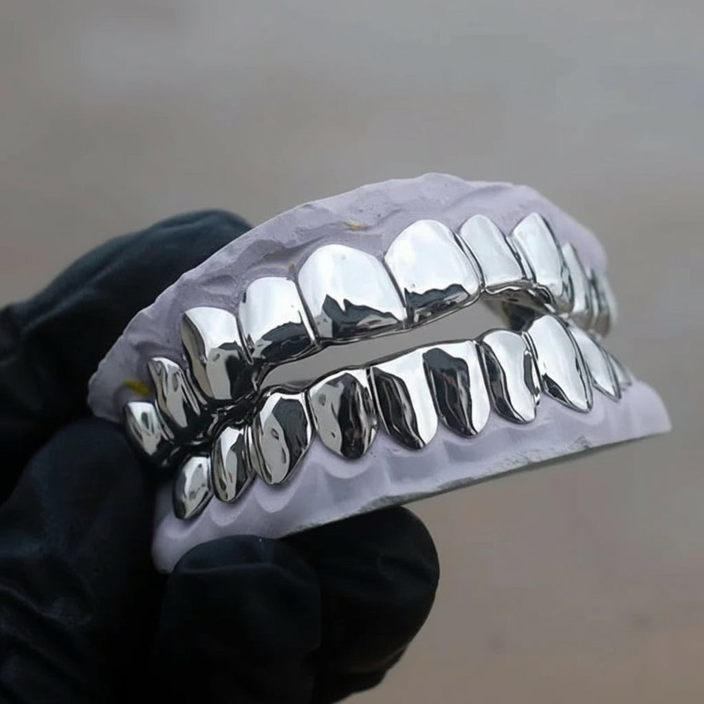 Metallic grill on teeth held by a gloved hand